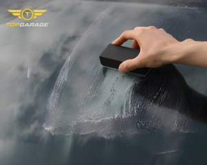 Hình ảnh thể hiện quá trình vệ sinh oto toàn diện với thao tác làm sạch kính lái bằng dụng cụ chuyên dụng, giúp loại bỏ bụi bẩn và hơi nước, mang lại tầm nhìn trong suốt khi lái xe. Dịch vụ vệ sinh oto toàn diện không chỉ chú trọng đến khoang động cơ mà còn chăm sóc từng chi tiết nhỏ như kính, nội thất và ngoại thất, đảm bảo chiếc xe luôn sạch sẽ, sáng bóng và an toàn khi vận hành.